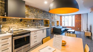Une cuisine moderne dotée d’un four encastré, d’un évier et d’un grand luminaire suspendu noir.