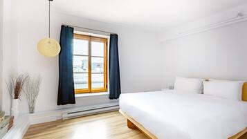 Ein modernes Schlafzimmer mit einem großen Bett, einem Fenster mit Vorhängen, einer Pendelleuchte und einer Heizung.
