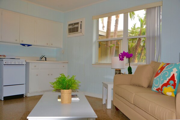 A kitchen with white cabinets, a white stove, and a small table with a plant.