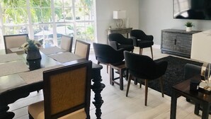 Un salon moderne comprenant un coin repas, un téléviseur à écran plat et une grande fenêtre donnant sur un paysage verdoyant.