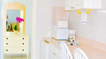 Una cocina con armarios blancos, una encimera, un fregadero y una silla.