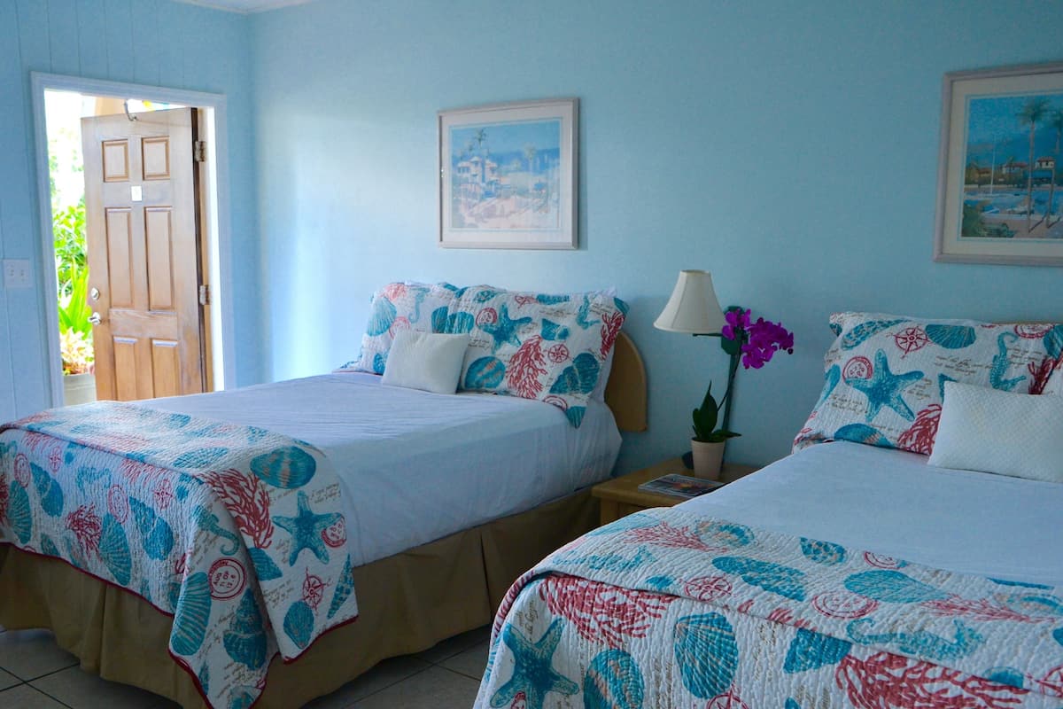 A bedroom with two beds, each with a starfish-themed bedspread, a nightstand with a lamp, and a framed picture on the wall.