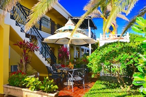 A courtyard with a dining area, outdoor seating, and a staircase leading to an upper level.