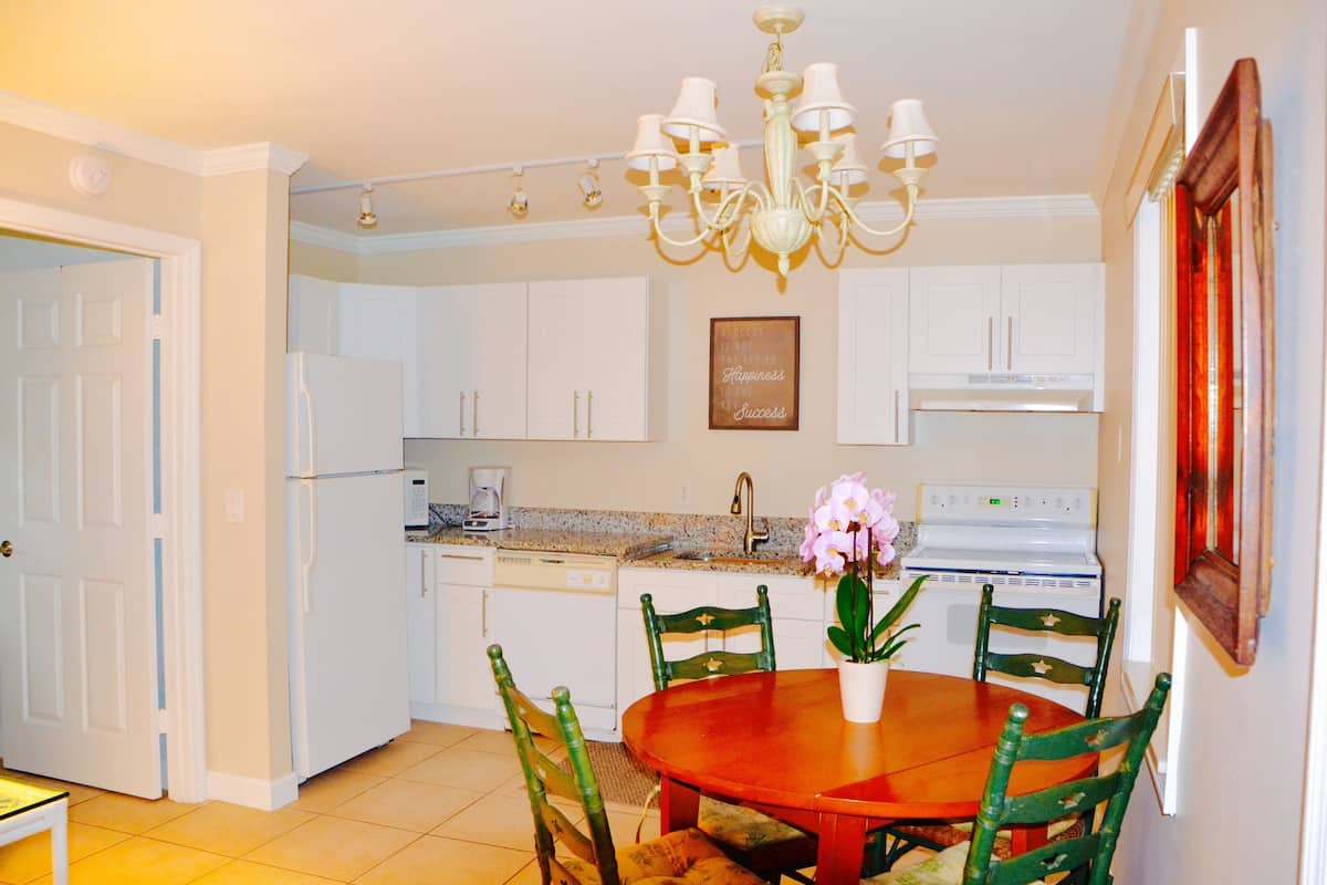 A kitchen with white cabinets, a stove, and a dining table with chairs.