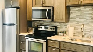 Une cuisine moderne dotée d’appareils électroménagers en acier inoxydable, de meubles en bois et d’un revêtement mural en carreaux.
