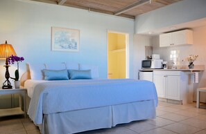A bedroom with a bed, bedside table, lamp, and a potted plant.