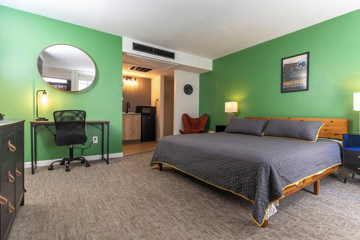 Une chambre comprenant un lit, un bureau, une chaise et une petite kitchenette.