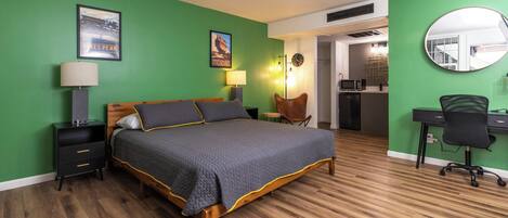 A bedroom with a bed, a desk, a chair, a lamp, a clock, and a poster on the wall.
