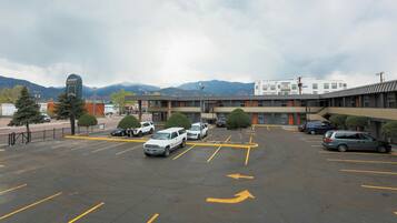 A parking lot with several cars, a motel building, and mountains in the background.