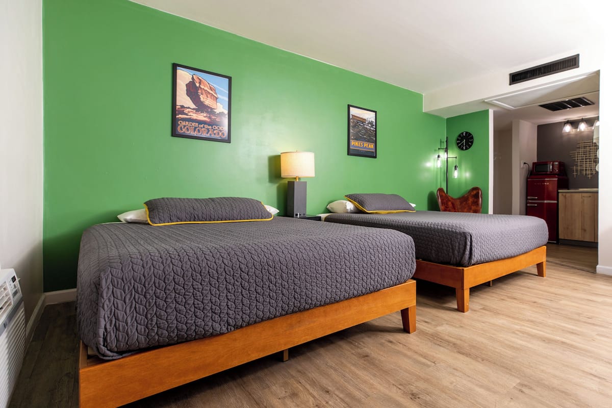 Une chambre avec deux lits, un bureau, une chaise, un four à micro-ondes et une horloge au mur.