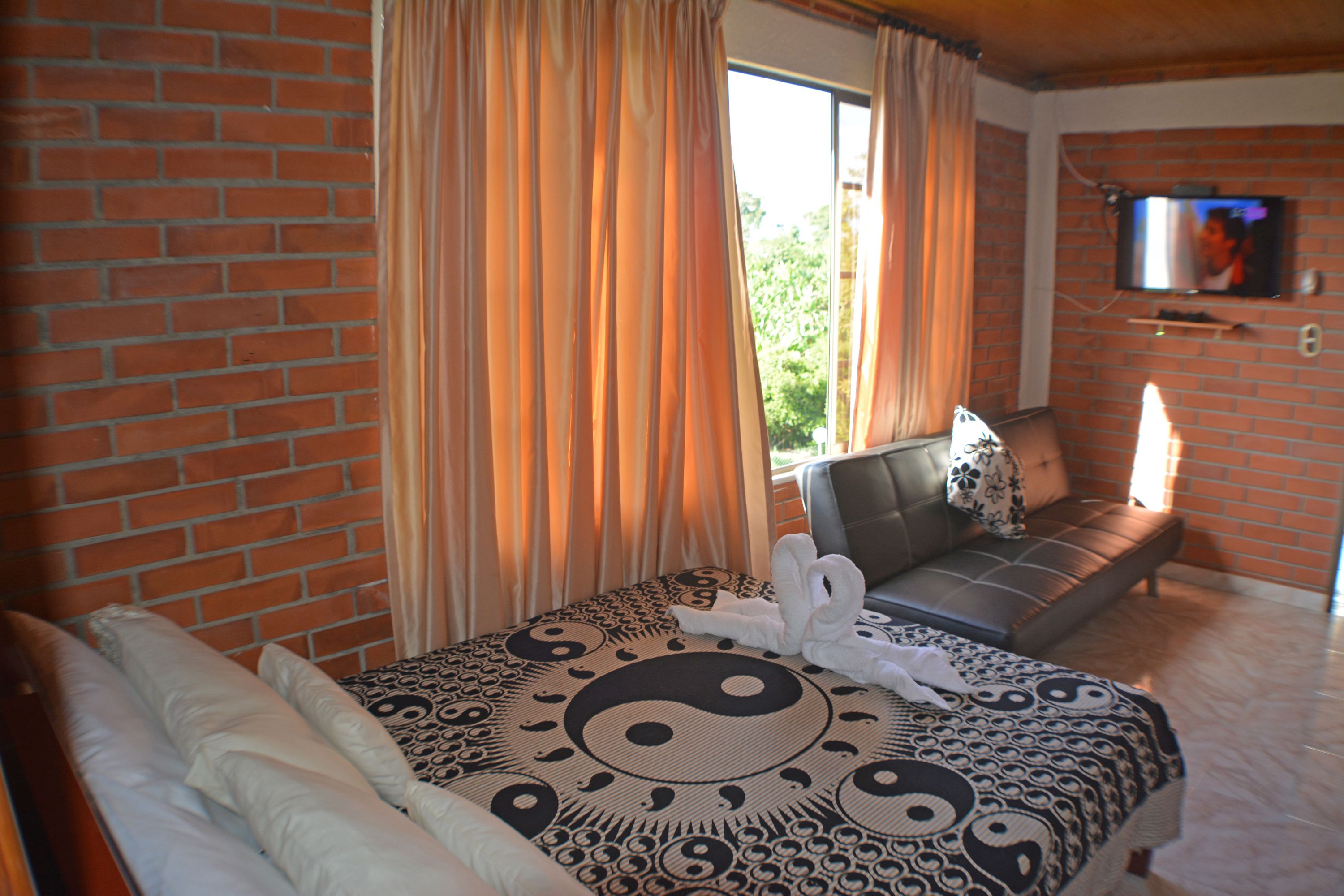 Una habitación de hotel con cama, sofá y televisión montada en la pared.