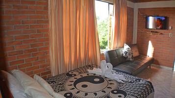 Una habitación de hotel con cama, sofá y televisión montada en la pared.
