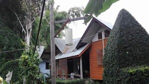 Una casa di legno rustica con tetto spiovente, immersa nel verde e circondata da un giardino curato.