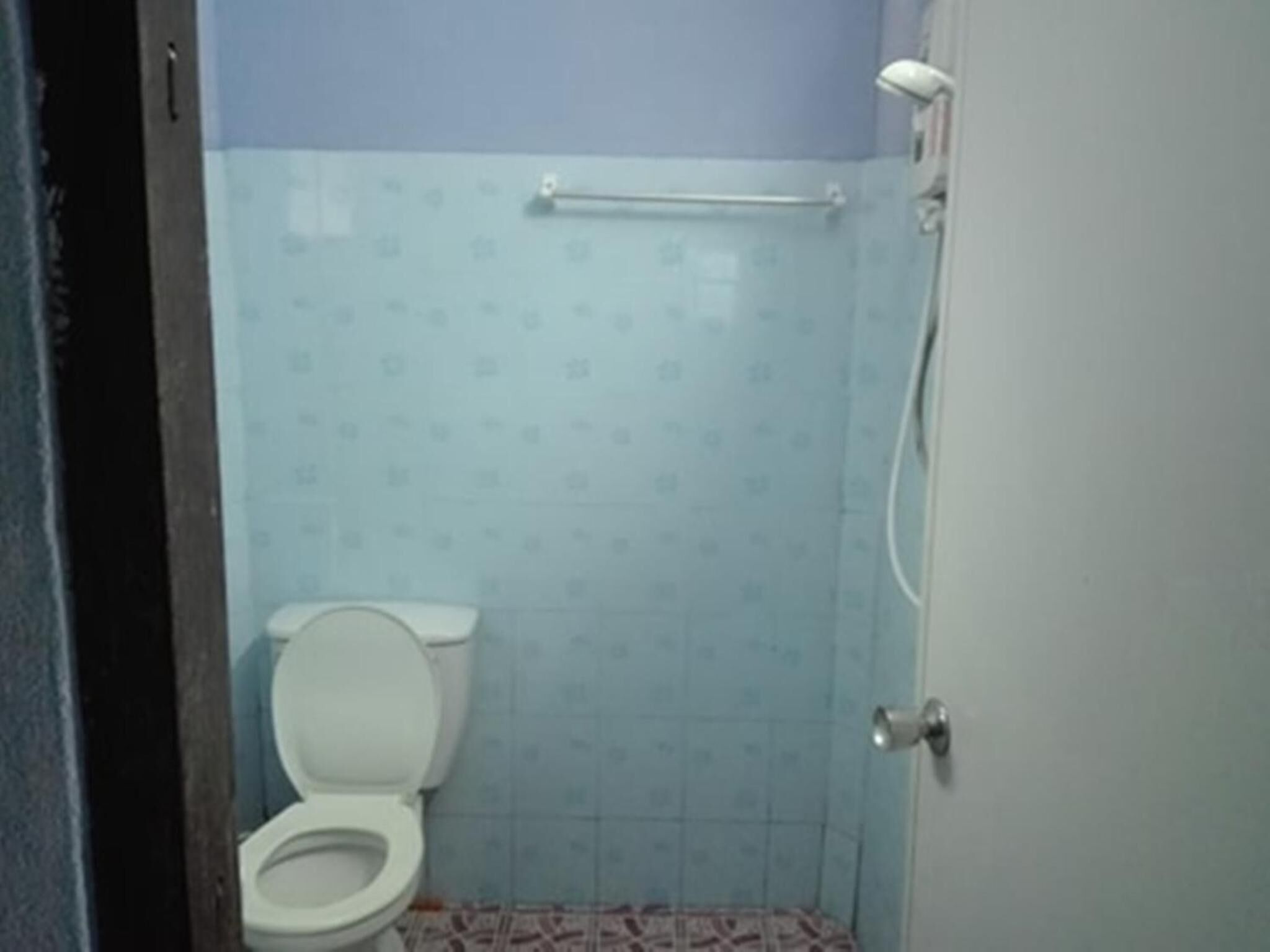 A bathroom with a toilet, a shower, and a towel rack.