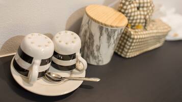 Two salt and pepper shakers on a white plate with a spoon, a marble mug, and a checkered box.