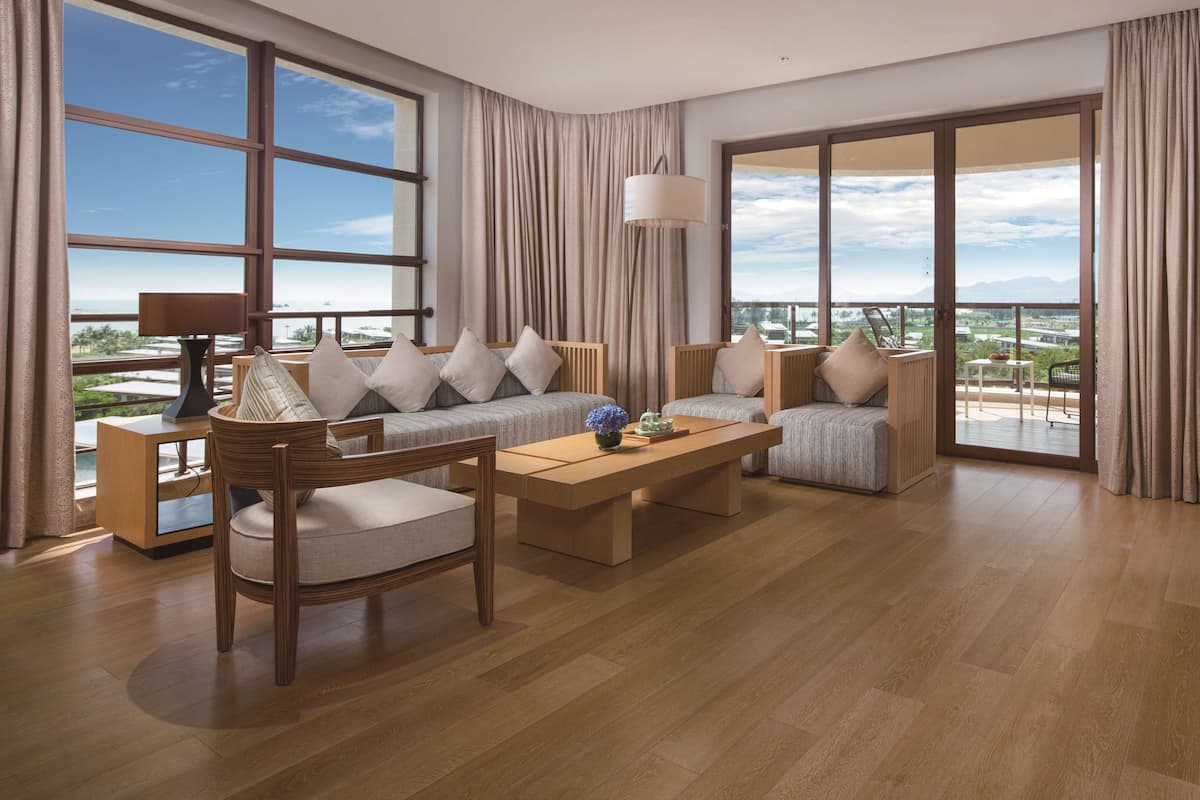 A spacious living room with a large window offering a city view, a wooden coffee table, and a comfortable seating area.