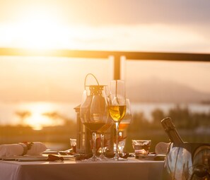 A table set for a meal with wine glasses, a bottle, and a candle, overlooking a scenic view. - Thousand Cranes Sanya Yazhou Bay Int'l Exchange Centre  (Sanya)