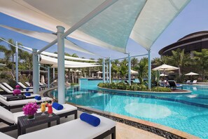 A poolside area with lounge chairs, umbrellas, and a clear blue pool. - Thousand Cranes Sanya Yazhou Bay Int'l Exchange Centre  (Sanya)