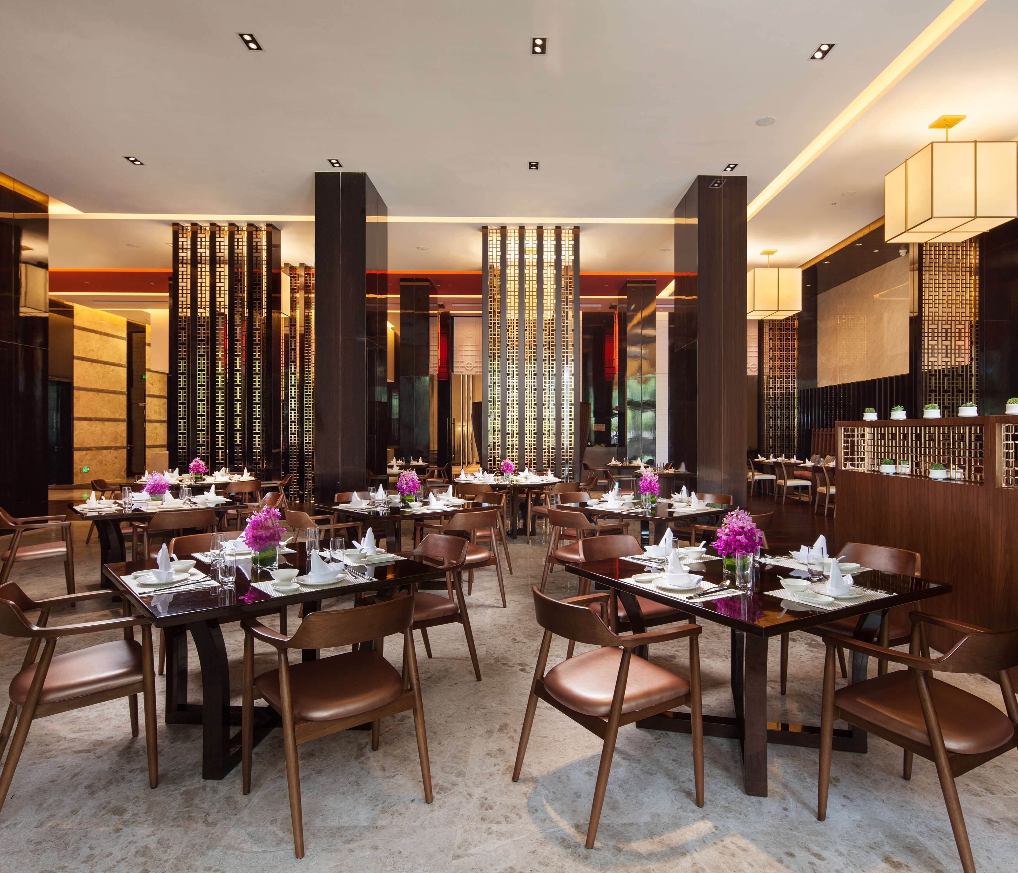 Een modern restaurant met meerdere tafels en stoelen, met een warme inrichting en houten details en decoratieve panelen.