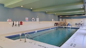 Une piscine intérieure équipée de panneaux de signalisation de sécurité, de bouées de sauvetage et d’un panneau indiquant la capacité maximale de la piscine.