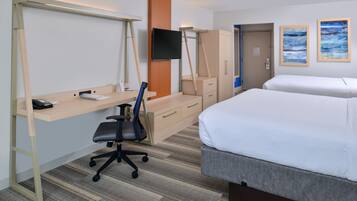 A hotel room with a desk, chair, bed, wardrobe, and a TV.