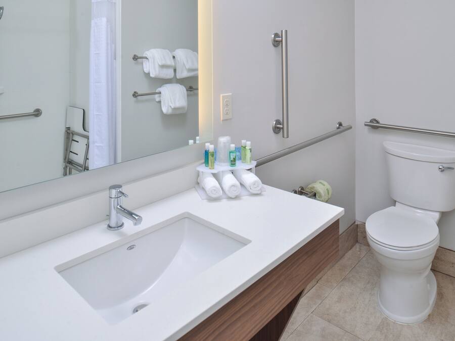 A modern bathroom with a sink, mirror, and toilet.