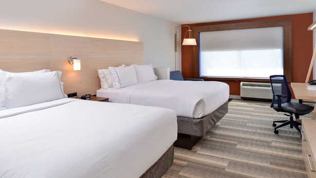 Ett hotellrum med två sängar, ett skrivbord och ett stort fönster.