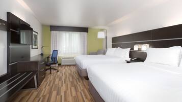 A hotel room with two beds, a desk, a chair, a TV, and a window with curtains.