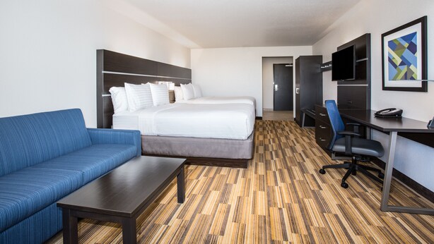 Una habitación de hotel con cama, sofá, escritorio, televisor y un cuadro en la pared.
