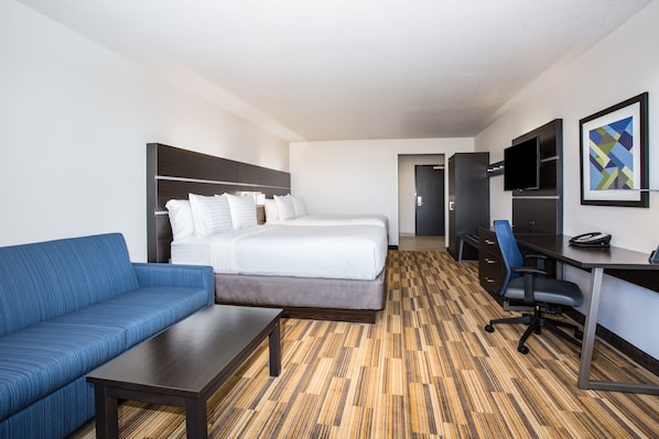 Una habitación de hotel con cama, sofá, escritorio, televisor y un cuadro en la pared.