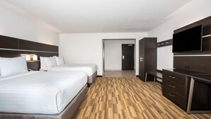 Habitación de hotel con dos camas, televisión de pantalla plana, escritorio y vestidor.