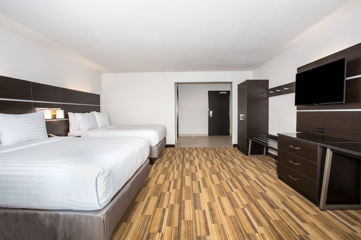 Habitación de hotel con dos camas, televisión de pantalla plana, escritorio y vestidor.