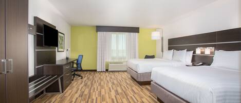 Une chambre d’hôtel avec deux lits, un bureau, une chaise, une télévision et une fenêtre avec des rideaux.