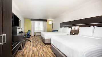 A hotel room with two beds, a desk with a flat-screen TV, a chair, and a window with curtains.