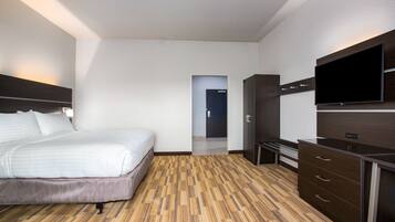Una habitación de hotel con cama, televisor, armario y suelo de madera.