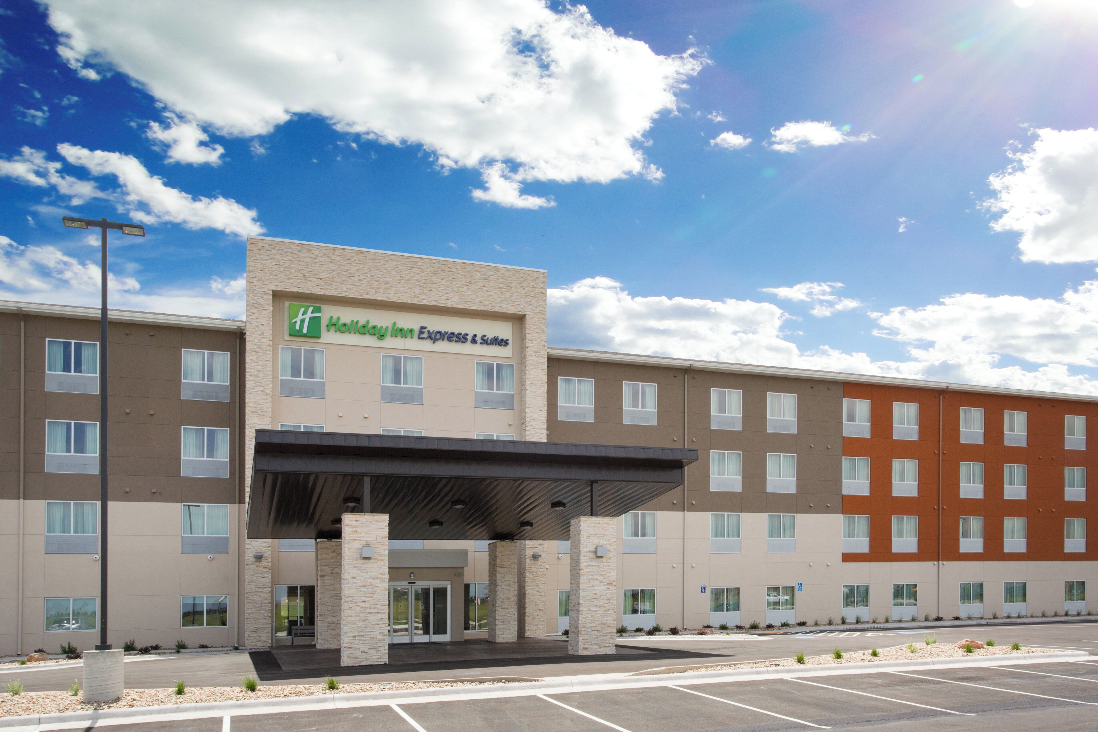 A Holiday Inn Express & Suites building with a modern design, featuring a covered entrance and multiple windows.