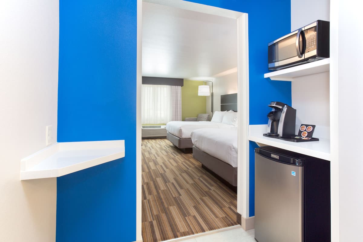 Habitación de hotel con cama, microondas, cafetera y refrigerador.