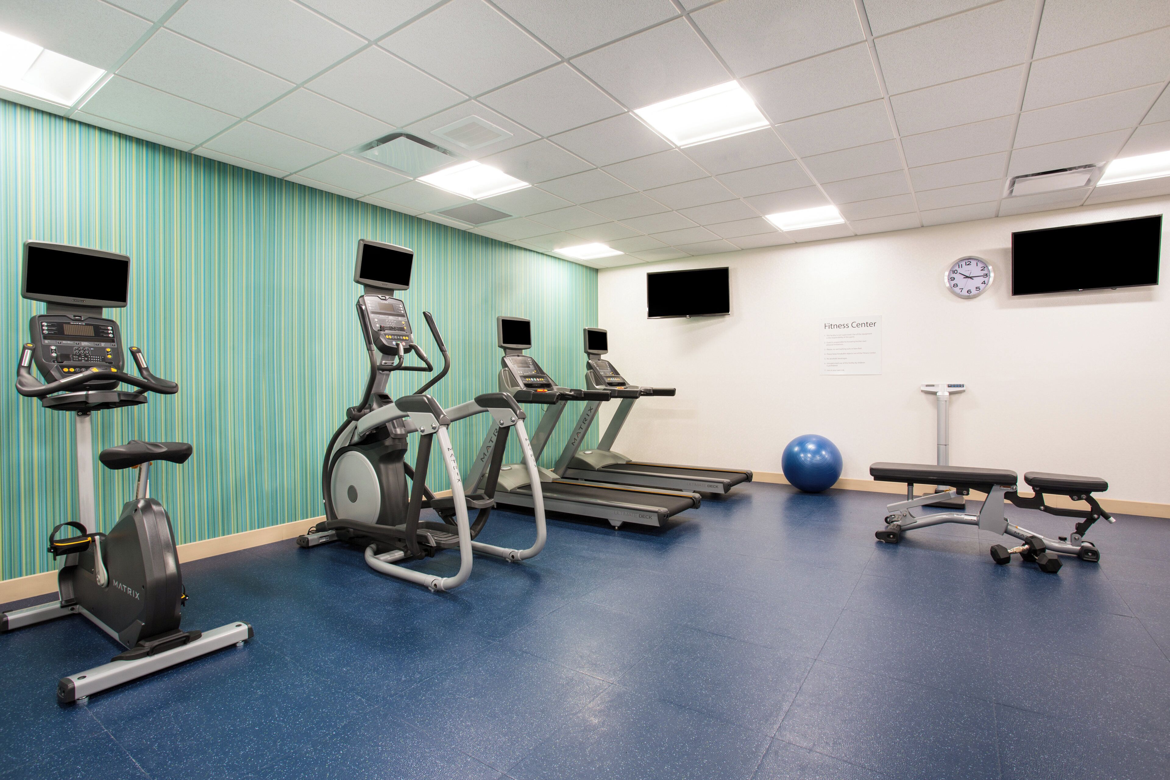 A fitness center with treadmills, an elliptical, a stationary bike, a bench, and a medicine ball.