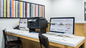 A reception desk with two monitors displaying a rewards program interface, a printer, and a keyboard.