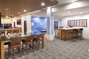 Un hall de hotel con zona de bar, asientos y mostrador de recepción.