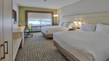 A hotel room with two beds, a desk, a chair, and a large window.