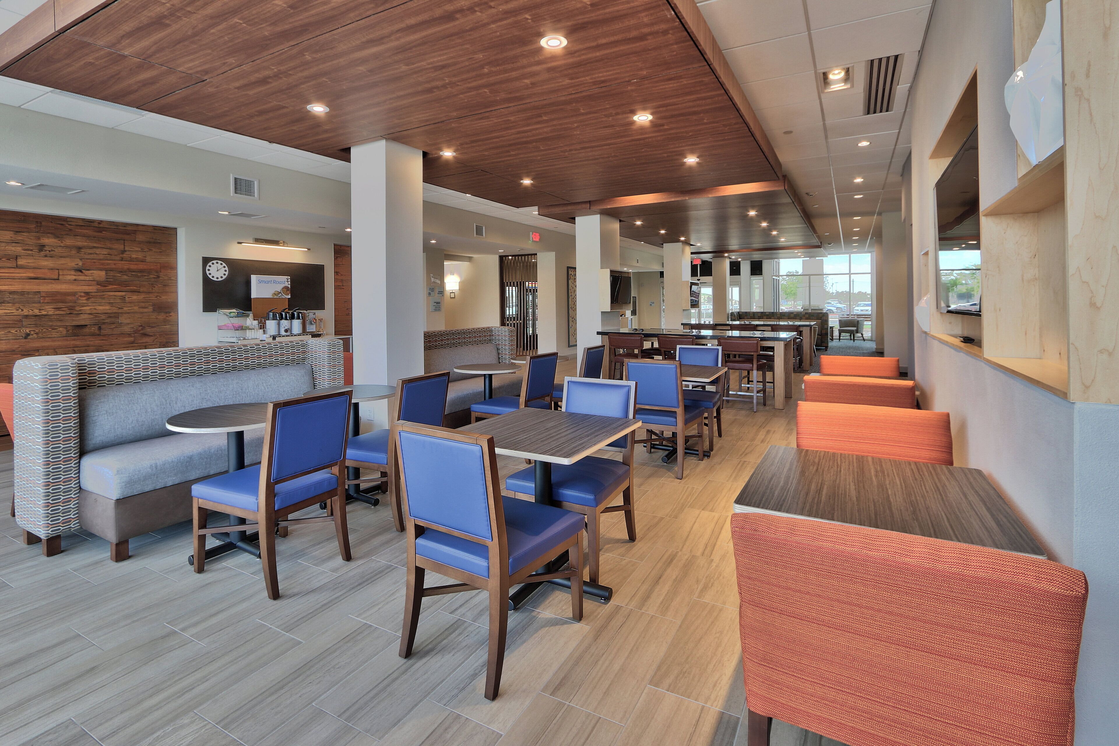 A modern restaurant with booths and tables, wooden ceiling, and large windows.