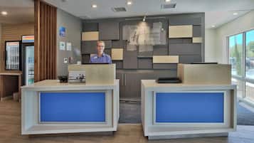 Un mostrador de recepción de hotel con diseño moderno, una placa y un cartel de Holiday Inn Express & Suites.