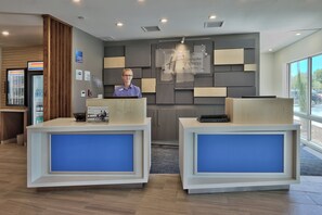 Balcão de recepção de hotel com design moderno, placa de identificação e sinalização para Holiday Inn Express & Suites.