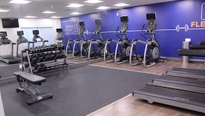 A gym with treadmills, elliptical machines, and a bench.