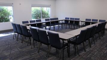 Una sala conferenze con un lungo tavolo e sedie, ampie finestre e pavimento con moquette.