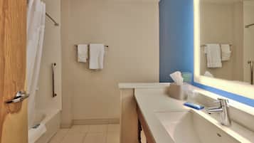 A bathroom with a bathtub, a sink, a mirror, and a towel rack.