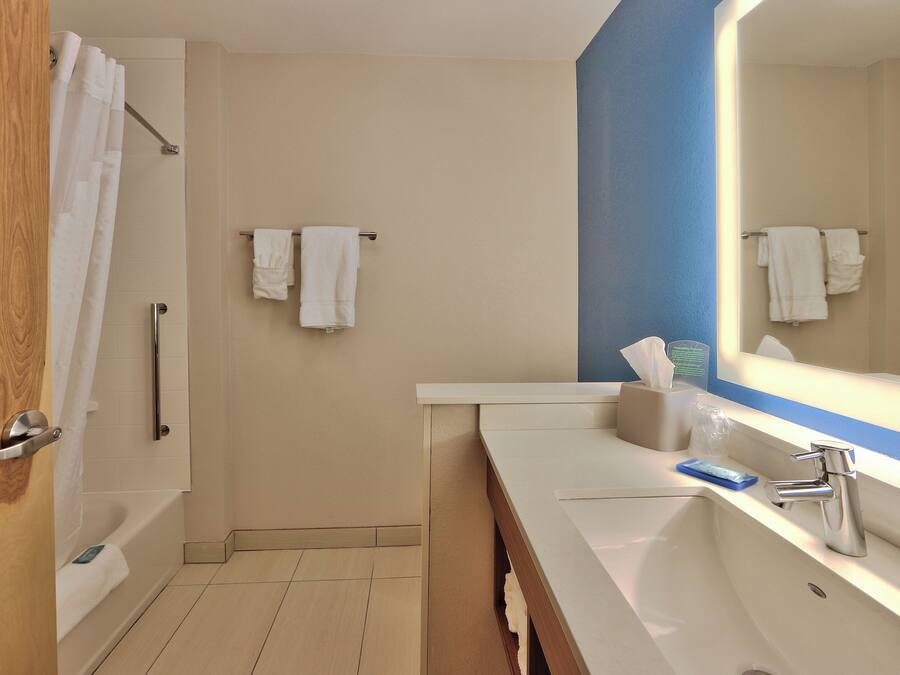 A bathroom with a bathtub, a sink, a mirror, and a towel rack.