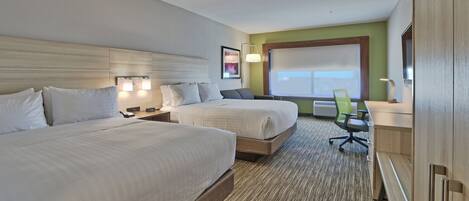A hotel room with two beds, a desk, a chair, and a large window.