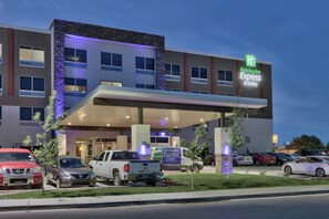A Holiday Inn Express & Suites hotel with a covered entrance, multiple parking spaces, and a clear sky. - Holiday Inn Express & Suites Roswell by IHG (Roswell)